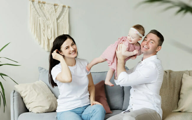 Happy family holding a baby on couch - Wellness Services Oxnard, CA